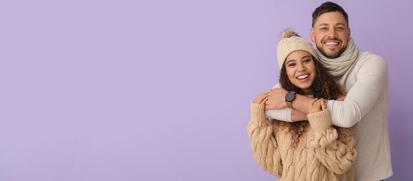 Happy hugging couple in winter clothes on color background