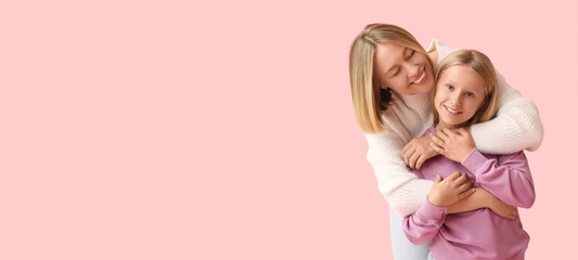 Beautiful woman hugging her cute daughter in stylish sweaters on pink background