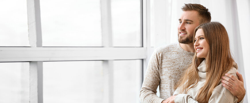 Happy couple resting near window at home