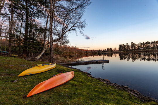 Kayaks on Lakeshore at Sunset with Calm Water and Floating Dock
