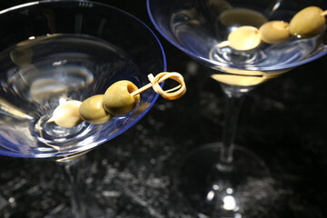 Glasses of tasty martini with olives on dark background, closeup