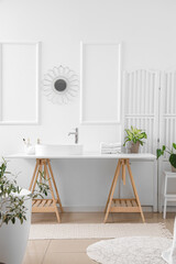 Interior of light bathroom with white sink, bath accessories and houseplants
