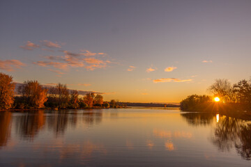 Obraz premium Colorful fall leaves with beatiful sunset on the lake
