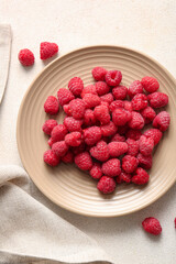 Plate with fresh raspberries on white background