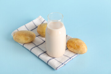 Bottle of tasty potato milk on blue background