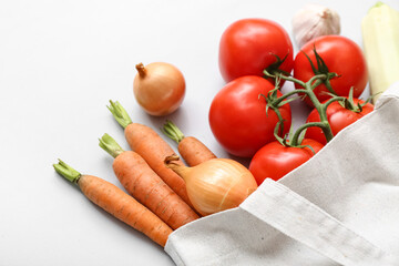 Eco bag with different fresh vegetables on light background, closeup