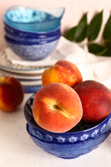 Bowl with sweet peaches on white table
