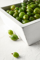 Basket with fresh gooseberries on white background, closeup