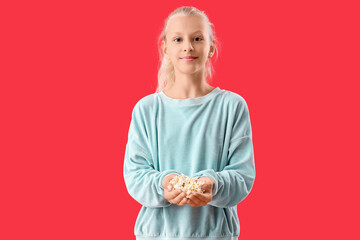 Happy girl holding popcorn on red background