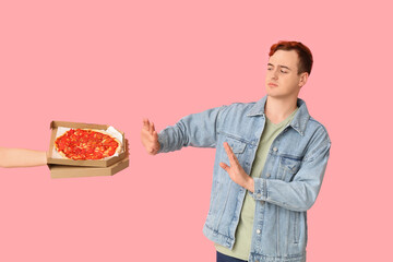 Young man refusing tasty pizza on pink background