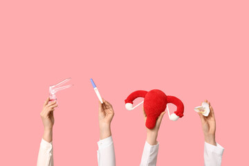 Doctor's hands with female uterus, pregnancy test and gynecological speculum on pink background © Pixel-Shot