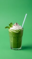 A vibrant green smoothie topped with whipped cream, chocolate sprinkles, and fresh mint leaves against a matching green background