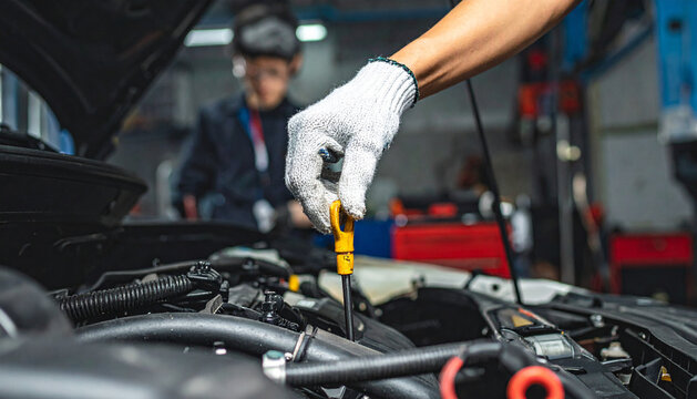 Mechanic inspecting a car engine oil dipstick for level check in a workshop