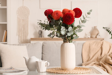 Dahlia flowers in vase, teapot and cup on glass table in living room