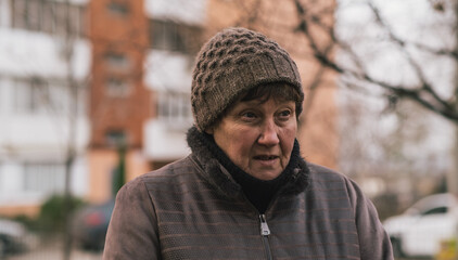 Elderly woman reflecting thoughtfully in urban park during a cool afternoon in early autumn