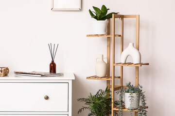 Chest of drawers and shelving unit near white wall in interior of room, closeup