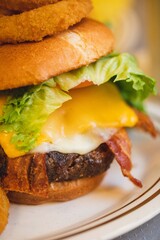 A bacon cheeseburger with onion rings served at a brightly lit American restaurant 