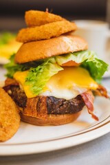 A bacon cheeseburger with onion rings served at a brightly lit American restaurant 