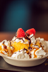 A close up of fried ice cream topped with whipped cream, chocolate, blackberries and raspberries at a modern food restaurant 