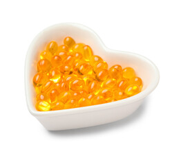 Heart shaped bowl with vitamin E capsules on white background