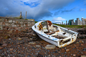 Small boat shipwrecked and decomposing on a rocky beach on the coast of the black isle, Scottland,...