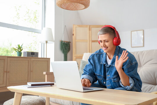 Young woman in headphones with short hair and laptop video chatting at home