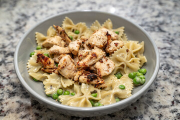 Bowtie past with peas and garlic chicken Alfredo in a grey dish 