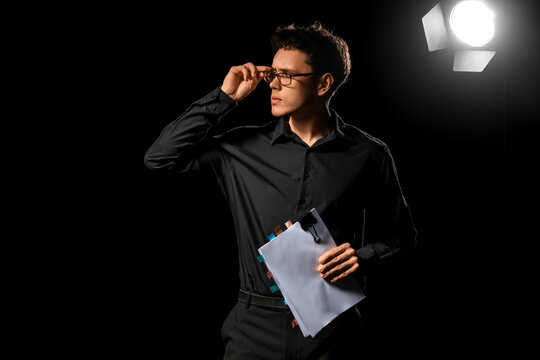Male screenwriter with scenario on dark background
