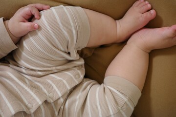 Close-up of baby's legs and feet resting on a nursing cushion, representing growth and Japanese parenthood