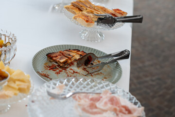 Delicious party food selection arranged on elegant serving dishes with tongs ready for guests to serve themselves at an indoor event
