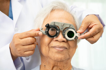 Asian senior woman wearing ophthalmic vision eye test and using optical trial frame.