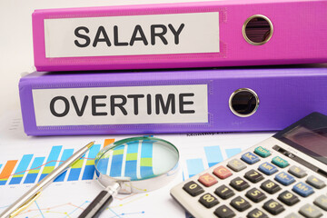 Salary, Overtime. binder with graph and calculator in business office.