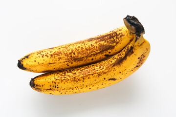 Two overripe bananas showing natural brown spots on their peel, placed on a white background.