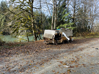 Abandoned camper in the woods changed to a house near the river for poor people living in poverty within the United States