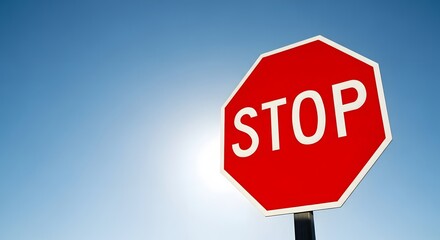 Obraz premium Bright blue sky with isolated red stop sign for traffic safety design and urban planning