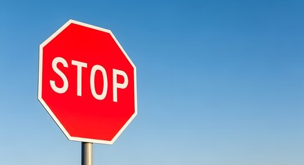 Obraz premium Red stop sign against clear blue sky for traffic safety awareness and road transportation design