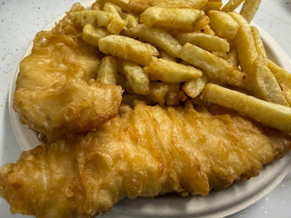 Appetizing Close-up of Golden Fried Cod Fish and Chips. Full Frame View of Crispy Battered Fillet and Thick Cut French Fries on a Plate