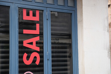 Shopfront promoting sale with bold red lettering