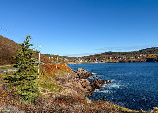 Scenic Coastal Drive to Maddox Cove, Newfoundland. Charming Village View from Rocky Shoreline with Autumn Colors and Bright Blue Atlantic Water
