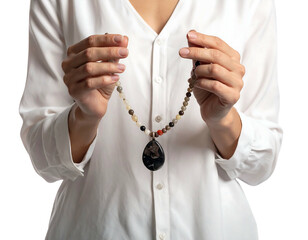 A woman in a white blouse holds a delicate necklace. The necklace is strung with beads and has a pendant