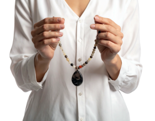 A woman in a white blouse holds a delicate necklace. The necklace is strung with beads and has a pendant