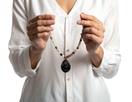 A woman in a white blouse holds a delicate necklace. The necklace is strung with beads and has a pendant