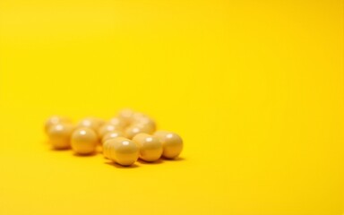 Close-up of yellow vitamin capsules on a yellow background. High quality