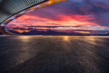 Asphalt road and bridge with dramatic sky clouds at sunset