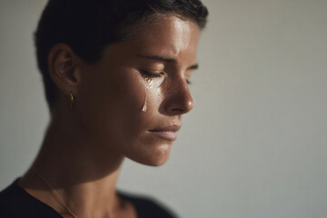 young woman with closed eyes and single tear on her cheek is captured in moment of deep contemplation