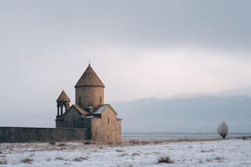 stone church stands majestically in snowcovered field under grey overcast sky