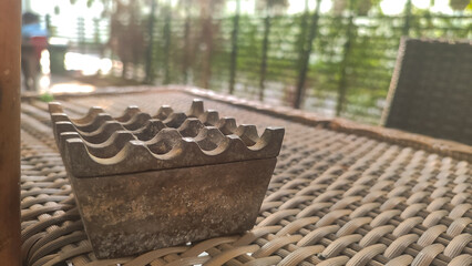 top view of metal ashtray on rattan woven table