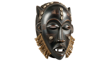 Elaborate dark wooden tribal mask adorned with white shells and raffia fringe hangs against a black background