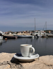 cup of coffee by the sea at the beach with boats in the port in Croatia