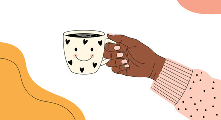 A hand with dark skin holds a cozy coffee mug decorated with hearts and a smiley face, set against a cheerful, abstract background.